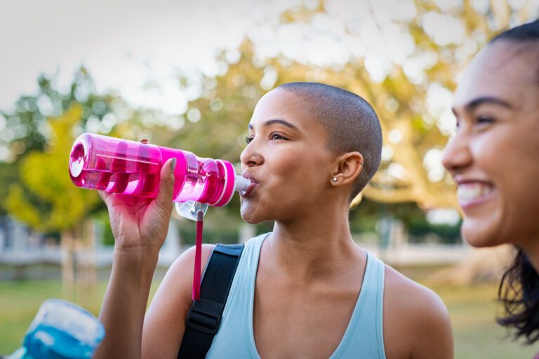 Sporty woman drinking water after exercise