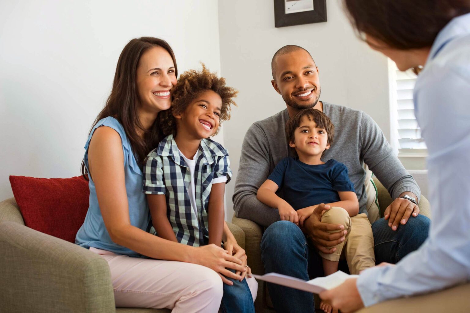 Smiling family sitting on a couch and talking to a provider