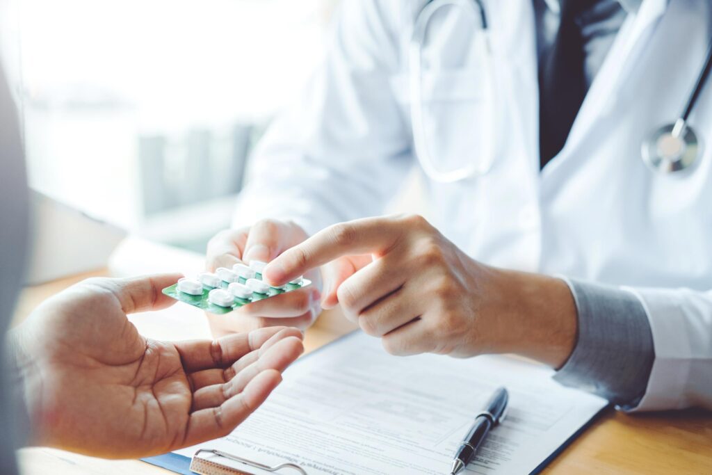 Closeup of doctors hands pointing to prescription pills while discussing with patient