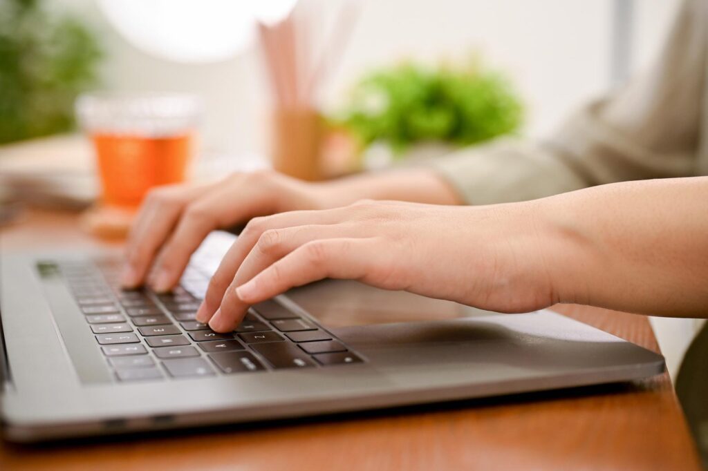 A female's hands typing on notebook laptop keyboard, using laptop computer.