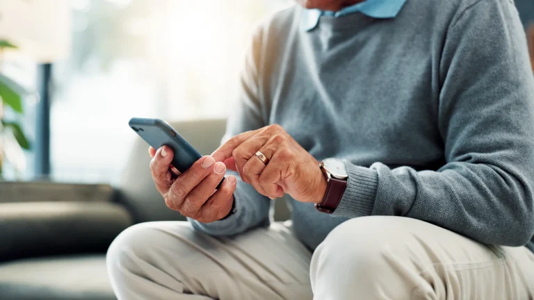 older man holding cell phone for teladoc