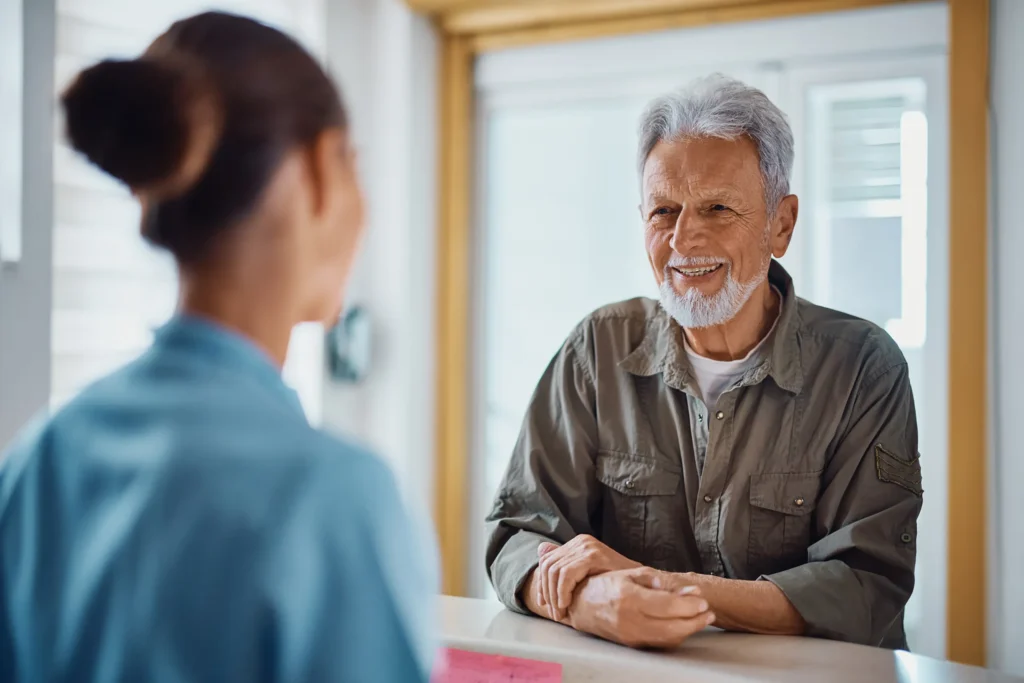 senior man talking to hospital receptionist