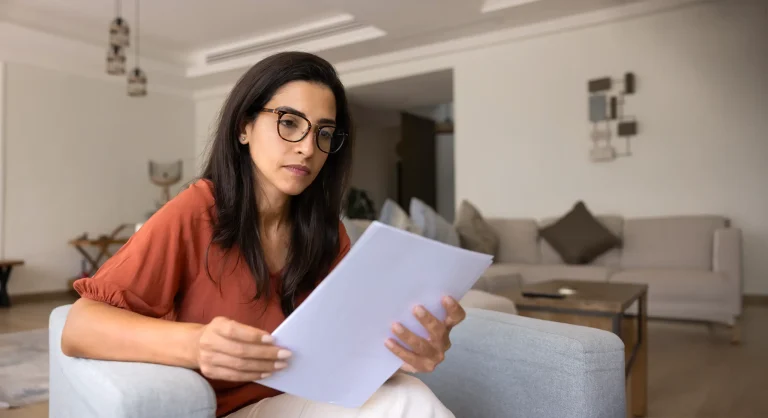 woman looking at paper sitting at home